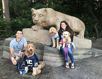 Family with dogs sitting in front of Nittany Lion statue