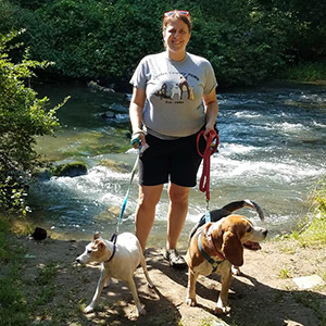 Megan standing by the river with two dogs