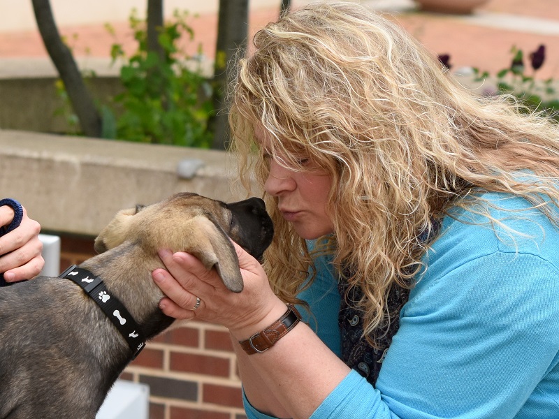 PAWS volunteer embracing a dog.