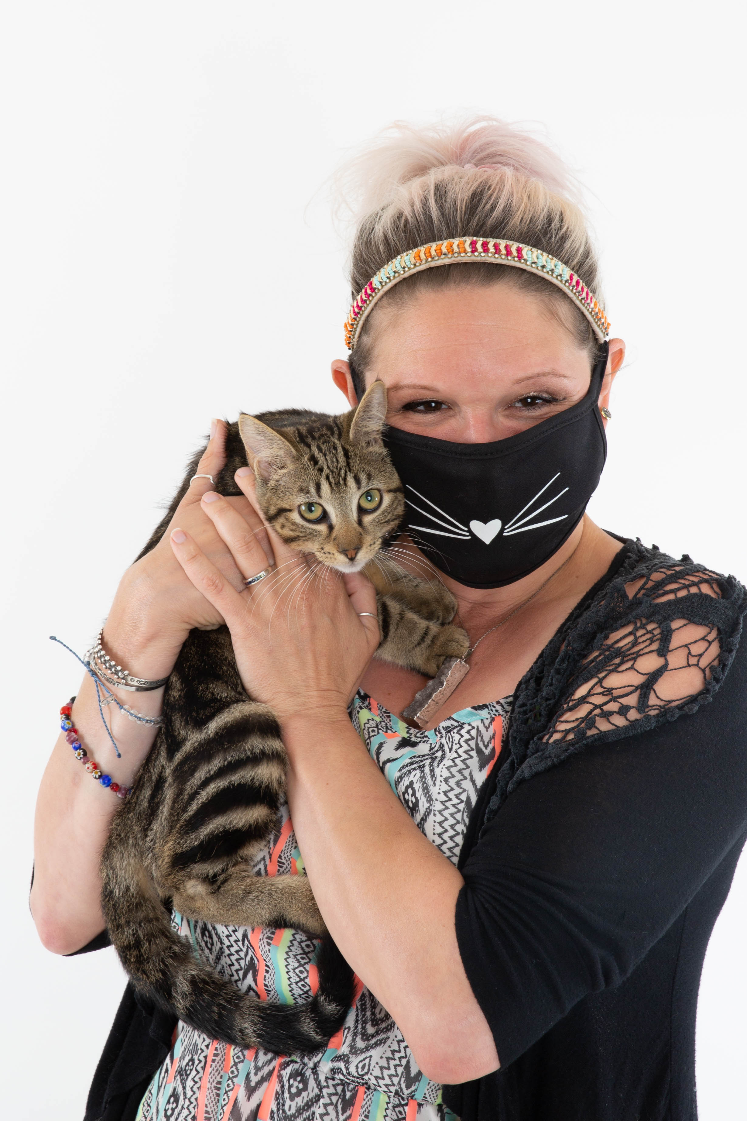 Masked staff person with brown tabby cat