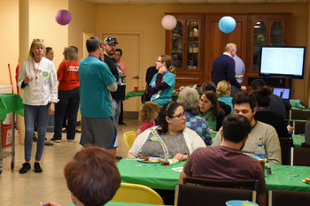 People gather for food and drinks around tables at PAWS